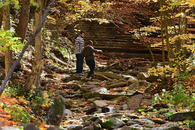 People walk in a dried up creek among the fall foliage at John Boyd Thacher State Park on Oct. 15, 2020, in New Scotland. While it may look like fall with foliage transitioning, it won’t feel like fall this weekend. This weekend will be around 10 to 15 degrees warmer than average. It will seem like summer has returned as highs soar to near 80 on Saturday, and into the lower 80s on Sunday.