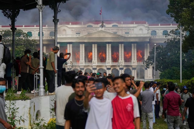 Protesters take selfies and celebrate on Sept. 9, 2025, at the Singha Durbar, the seat of Nepal's government ministries and offices, after it was set on fire during a protest against  a social media ban and corruption in Kathmandu, Nepal. (Niranjan Shrestha/AP)