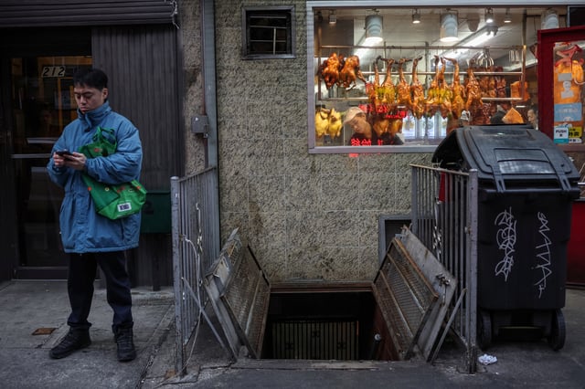 A woman works in a restaurant as a man checks his mobile in the Chinatown area of New York City, U.S., January 1, 2025. REUTERS/Marko Djurica