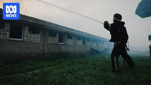 A man fights a fire in a building while surrounded by smoke