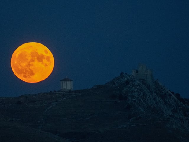 Harvest moon shining behind Rocca Calascio Castle, Abruzzo, Italy on October 1, 2020.