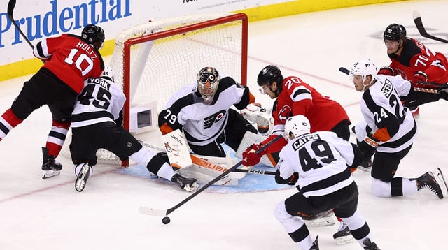 Dec 15, 2022; Newark, New Jersey, USA; New Jersey Devils center Michael McLeod (20) plays the puck after a save by Philadelphia Flyers goaltender Carter Hart (79) during the third period at Prudential Center. Mandatory Credit: Ed Mulholland-Imagn Images