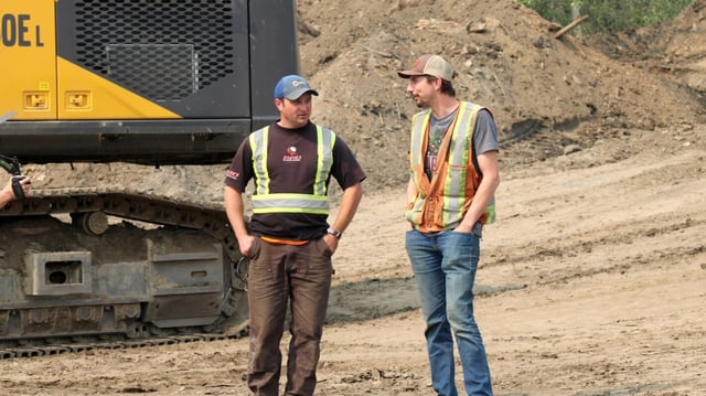 Mitch Blaschke and Parker Schnabel stood chatting next to excavator, 'Gold Rush', Season 16