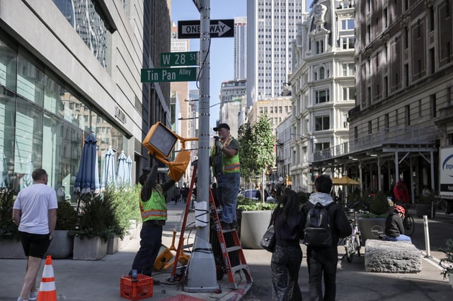 Workers fix a traffic light in New York City, U.S., October 1, 2025. REUTERS/Jeenah Moon