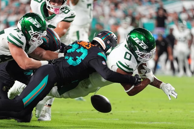 New York Jets running back Braelon Allen (0) fumbles the ball after taking a hit from Miami Dolphins cornerback Jack Jones, rear, in the first half of an NFL football game, Monday, Sept. 29, 2025, in Miami Gardens, Fla. (AP Photo/Rebecca Blackwell)
