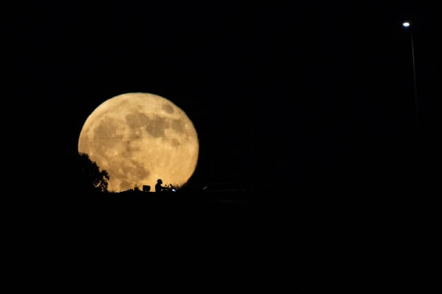 FILE - The moon rises in the sky over a freeway as drivers pass between Haifa and Tel Aviv, Israel, Wednesday, Sept. 18, 2024. (AP Photo/Ariel Schalit, File)