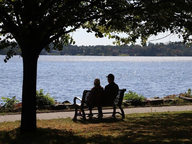 People relax on a bench overlooking Ramsey Lake in Sudbury. Sudburians are enjoying July-like weather this weekend. 
