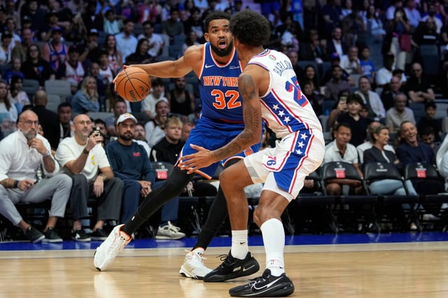 New York Knicks center Karl-Anthony Towns (32) looks to pass as Philadelphia 76ers forward Dominick Barlow defends during the first half of an NBA preseason basketball game in Abu Dhabi, United Arab Emirates, Sunday, Oct. 4, 2025. (AP Photo/Altaf Qadri)