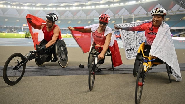 Canadian gold medallist Anthony Bouchard, centre, celebrates with silver medallist Tomoki Sato and bronze medallist Fabian Blum following the men's 100-metre T52 final at the World Para Athletics Championships.