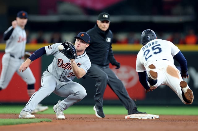 Dylan Moore #25 of the Seattle Mariners avoids a tag by Colt Keith #33 of the Detroit Tigers at T-Mobile Park on April 02, 2025 in Seattle, Washington.