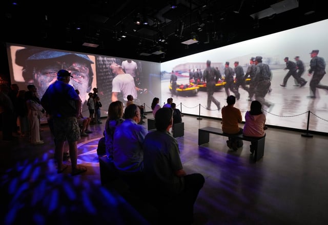 On Saturday, Oct. 4, 2025, in San Diego, visitors attending the grand opening of the Navy SEAL Museum watched a large three-screen display showcasing Navy SEALs in training and in action, including video interviews with former Navy SEALs.  (Nelvin C. Cepeda / The San Diego Union-Tribune)