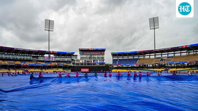 Groundmen cover the pitch as rain delays the start of the 2025 ICC Women's Cricket WC ODI match between Sri Lanka and Australia