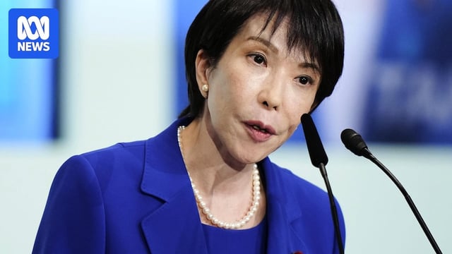 A woman with short black hair speaks into a microphone.
