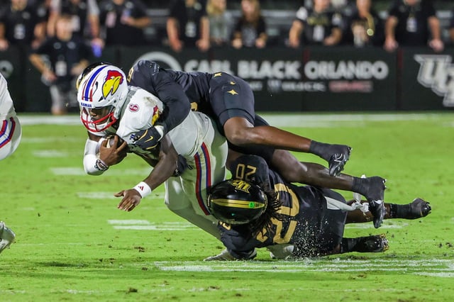 Oct. 4, 2025; Orlando, Florida; Kansas football quarterback Jalon Daniels (6) is tackled by UCF linebacker Lewis Carter (20) and defensive end Isaiah Nixon (6) during the first quarter.