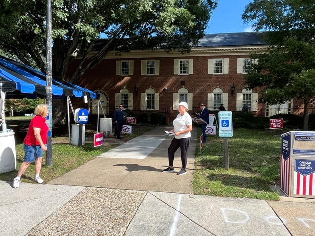 Political party volunteers wait to greet voters outside the early voting location in Virginia Beach, Virginia, U.S., October 2, 2025. REUTERS/Nathan Layne