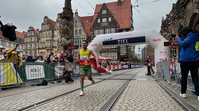 Ein Mann läuft mit hoch gerissenen Armen als erster durchs Ziel beim Bremen-Marathon