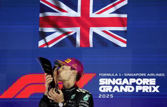 Formula One F1 - Singapore Grand Prix - Marina Bay Street Circuit, Singapore - October 5, 2025 Mercedes' George Russell celebrates on the podium with the trophy after winning the Singapore Grand Prix REUTERS/Athit Perawongmetha