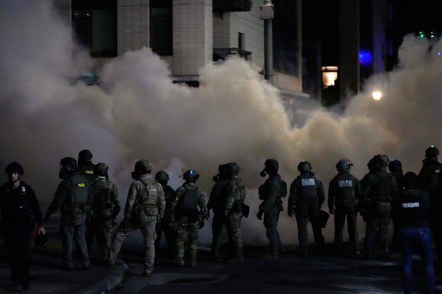 Law enforcement officers stand in tear gas outside a U.S. Immigration and Customs Enforcement facility during a protest on Saturday, Oct. 4, 2025, in Portland, Ore. (AP Photo/Jenny Kane)