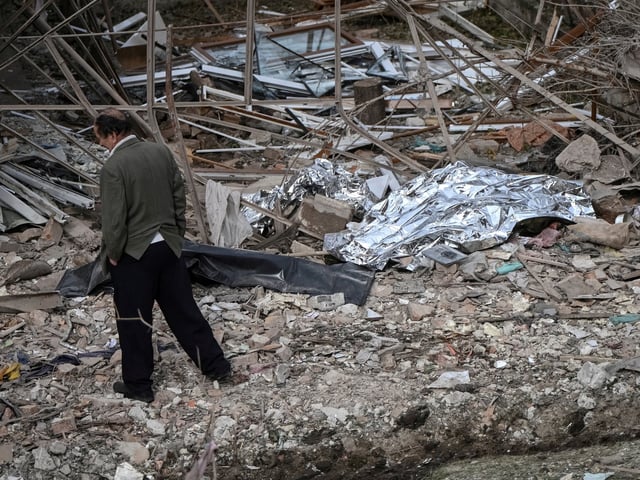 A man walks near the covered bodies of the victims of a Russian drone and missile strike, lying near their destroyed house, amid Russia's attack on Ukraine, in the village of Lapaivka on the outskirts of Lviv, Ukraine October 5, 2025. REUTERS/Stringer     TPX IMAGES OF THE DAY