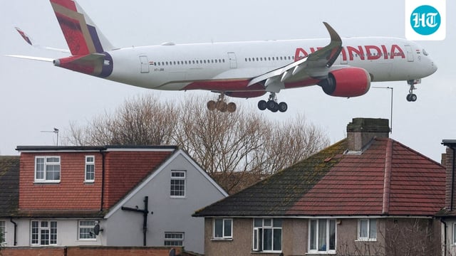 An Air India passenger plane flies near houses as it makes its landing approach.