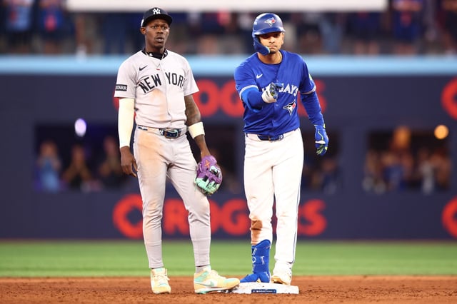 Andres Gimenez #0 of the Toronto Blue Jays celebrates after hitting an RBI double in front of Jazz Chisholm Jr. #13 of the New York Yankees during the eighth inning of game one of the Division Series at Rogers Centre on October 04, 2025 in Toronto, Ontario.