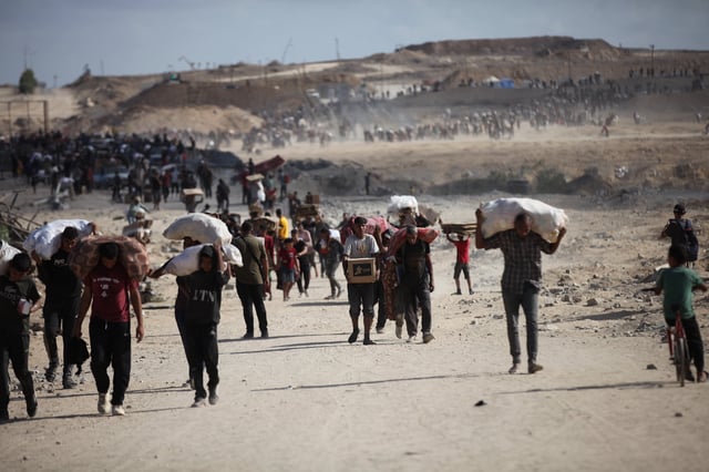 Palestinos llevan sacos y cajas de comida en la zona de Netzarim, en Gaza, donde multitudes se reunieron en un punto de distribución de ayuda