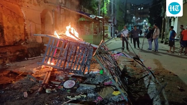 People gather near objects set ablaze after fresh incidents of violence linked to a group clash two days ago during a Durga idol immersion procession in Cuttack, Odisha