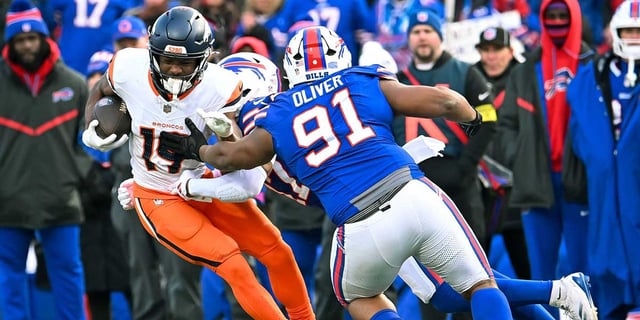 Jan 12, 2025; Orchard Park, New York, USA; Denver Broncos wide receiver Marvin Mims Jr. (19) is tackled by Buffalo Bills defensive tackle Ed Oliver (91) and cornerback Christian Benford (47) in the fourth quarter of an AFC wild card game at Highmark Stadium. Mandatory Credit: Mark Konezny-Imagn Images