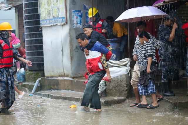 A Nepali man rescues an elderly woman from a flooded area in Kathmandu, Nepal, on October 4, 2025. Residential areas along the riverbanks of Kathmandu are inundated due to the continued influence of moisture-laden monsoon winds from the Bay of Bengal, which trigger heavy rainfall in parts of the Himalayan nation. In Nepal, the monsoon is particularly influenced by the Bay of Bengal, making it a major driver of monsoon-related disasters. During the four months of the monsoon season, starting from June to September, Nepal typically receives around 80% of its annual average rainfall of 1,600 mm, sometimes reaching up to 1,800 mm. Nepal ranks second after Bangladesh in South Asia and 20th globally in multi-hazard disaster risk. According to the 2019 Asian Development Bank report, floods alone cause an average annual loss exceeding USD 140 million, accounting for 1.4% of Nepal's GDP. (Photo by Subaas Shrestha/NurPhoto via Getty Images)