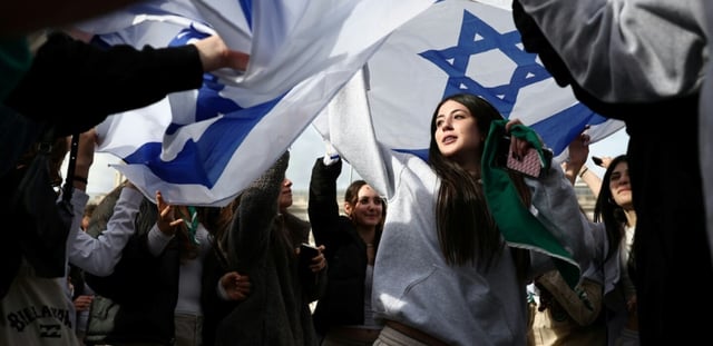 Des personnes dansent sous des drapeaux israéliens lors d'un événement commémoratif organisé par la communauté juive pour honorer les vies perdues lors de l'attaque du Hamas le 7 octobre 2023, à Londres, le 5 octobre 2025