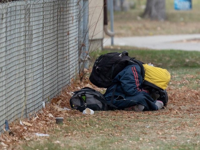 A person tries to stay warm on 20th Street in November, 2024.