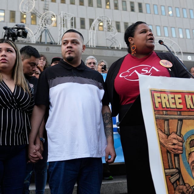 Jennifer Vasquez Sura, front left, and her husband Kilmar Abrego Garcia, front center, attend a protest rally at the Immigration and Customs Enforcement field office in Baltimore, Monday, Aug. 25, 2025, to support Kilmar Abrego Garcia. (AP Photo/Stephanie Scarbrough)
