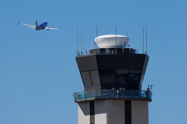 A commercial airliner takes off past the air traffic control tower at San Diego International Airport during the first day of a partial U.S. government shutdown in San Diego, California, U.S., October 1, 2025.     REUTERS/Mike Blake