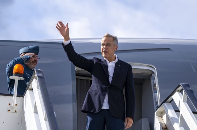 Prime Minister Mark Carney waves as he boards a government plane on Wednesday, Aug. 27, 2025. THE CANADIAN PRESS/Christinne Muschi