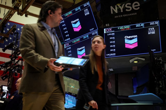 Traders work on the floor as screens display the logo for Chevron Corp. at the New York Stock Exchange (NYSE) in New York City, U.S., October 23, 2023.  REUTERS/Brendan McDermid/File Photo