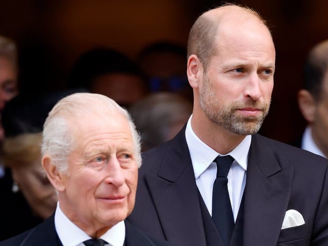 King Charles and Prince William wearing black suits and ties standing next to each other
