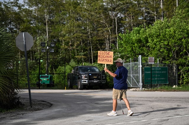 A member of "Leaders of Faith and Conscience" holds a placard during a weekly interfaith vigil outside the immigrant jail known as "Alligator Alcatraz" at the Dade-Collier Training and Transition Airport in Ochopee, Florida, on August 24, 2025.
