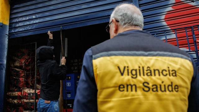 Un agente de vigilancia sanitaria cierra una bodega de licores durante un operativo el último jueves, en una bodega de la zona sur de Sao Paulo.