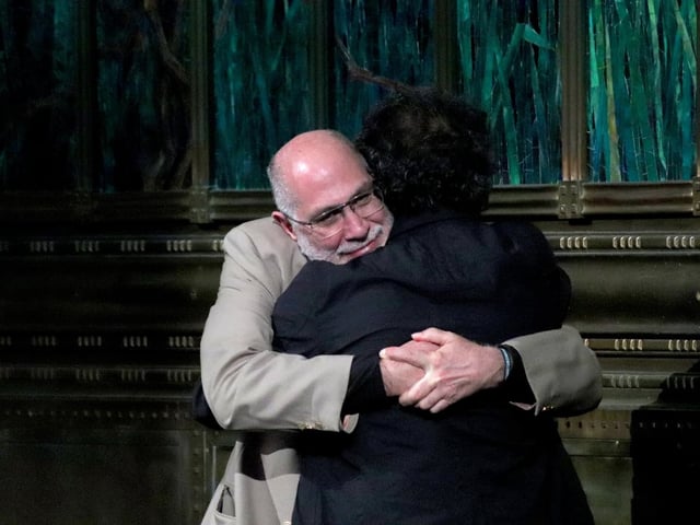 Guillermo Arriaga y Alejandro González Iñárritu se abrazan emotivamente sobre el escenario del Palacio de Bellas Artes durante la celebración por los 25 años de Amores perros, sellando así su reconciliación tras dos décadas de distanciamiento.