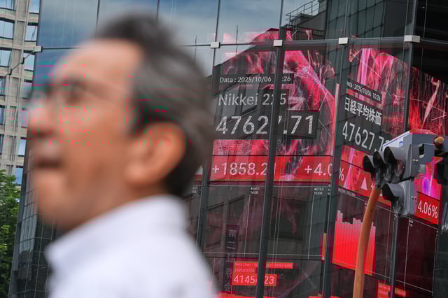 A person stand in front of an electronic stock board showing Japan's Nikkei index at a securities firm Monday, Oct. 6, 2025, in Tokyo. (AP Photo/Eugene Hoshiko)