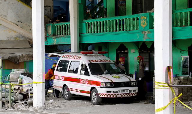 An ambulance stands by for victims at the site of a building where a hall collapsed while students were praying at the Al-Khoziny Islamic boarding school in Sidoarjo, East Java province, Indonesia, October 3, 2025. REUTERS/Dipta Wahyu