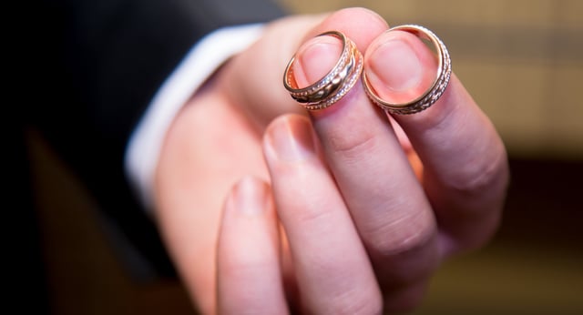 Gold wedding rings in the man’s hand. Close up.