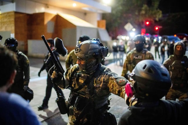 Police and federal officers stand guard at a US. Immigration and Customs Enforcement facility in Portland on Sunday, October 5, 2025.