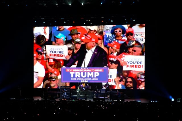 Le président argentin Javier Milei sur scène alors que des images du président américain Donald Trump sont projetées sur un écran géant lors du lancement de son nouveau livre, "La fabrique du miracle", à Buenos Aires, le 6 octobre 2025