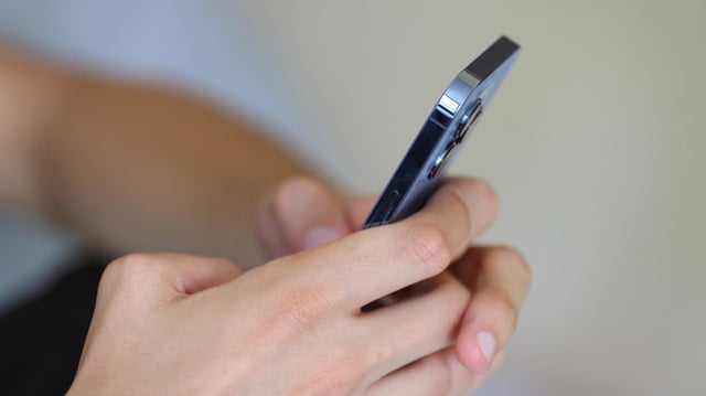 Hände halten ein Smartphone.