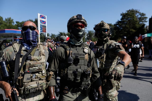 An Immigration and Customs Enforcement (ICE) agent (C) looks on as residents of Chicago's Brighton Park neighborhood confront law enforcement at a gas station after ICE agents allegedly detained an unidentified man riding in his car, in Chicago, Illinois, on October 4, 2025. US President Donald Trump, who campaigned on a pledge to deport large numbers of migrants, has encouraged authorities to be more aggressive as he seeks to hit his widely reported target of one million deportations annually.