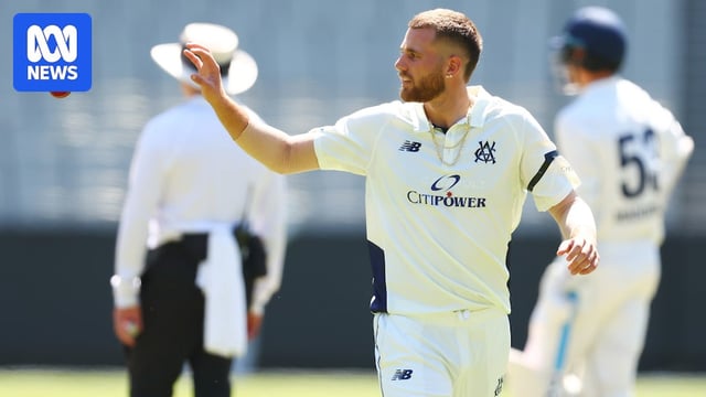 A bowler walking back to his mark, about to catch the cricket ball with one hand