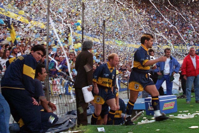 Maradona sale a la cancha ante una Bombonera eufórica por su regreso; detrás, Carlos Mac Allister