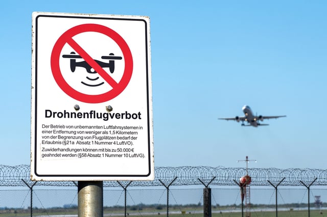 FOTOMONTAGE, Hinweisschild: Drohnenflugverbot, vor einem Flughafen. Symbolfoto für gesetzliche Regelungen, Sicherheitsmaßnahmen und Verbote zum Schutz des Luftraums und der Flugsicherheit vor Drohnen