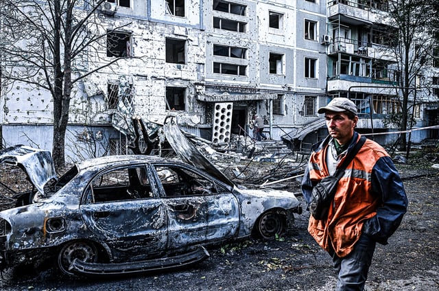A man walks past a calcinated car outside an apartment block damaged by a Russian strike, Zaporizhzhia, Ukraine, on October 5, 2025. Photo: Dmytro Smolienko/ Ukrinform / Alamy